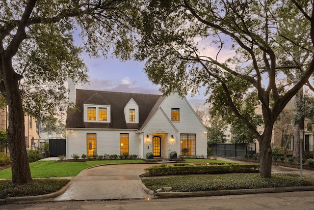 view of front of property with brick siding, a shingled roof, a front yard, and fence