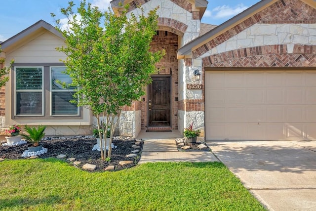 property entrance with stone siding, driveway, brick siding, and a garage