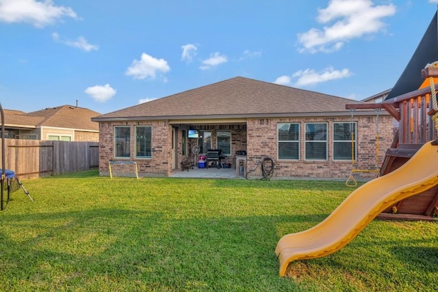 back of property featuring a playground, a fenced backyard, a patio area, a lawn, and brick siding