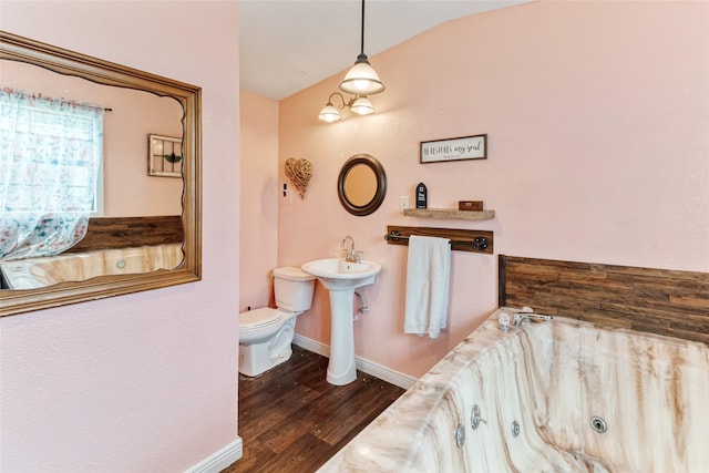 bathroom with a whirlpool tub, vaulted ceiling, wood finished floors, toilet, and baseboards