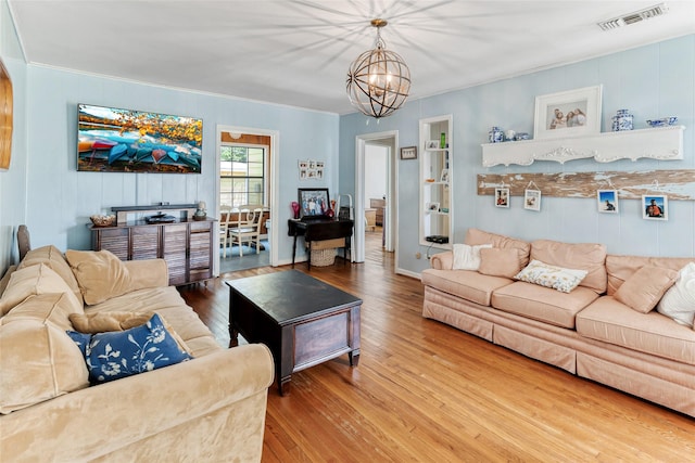 living area with visible vents, a chandelier, ornamental molding, and wood-type flooring