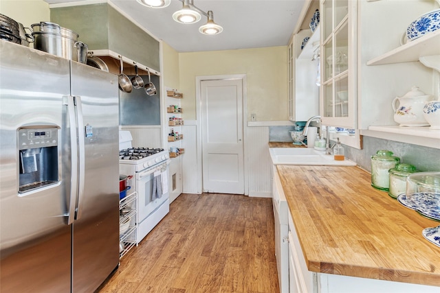 kitchen featuring stainless steel fridge with ice dispenser, white range with gas stovetop, a sink, light wood-style floors, and wood counters