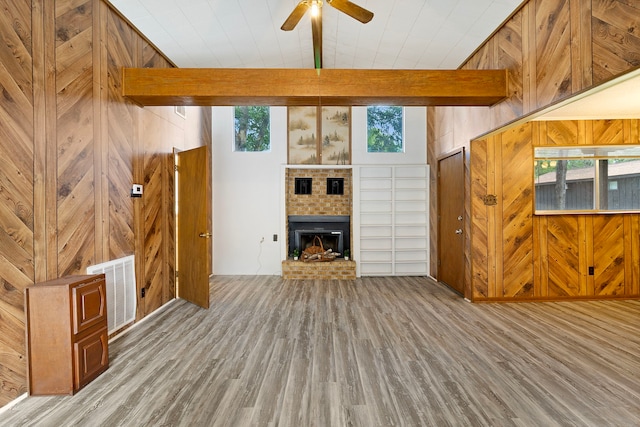 12 Walker Trl, Huntsville, TX 77320 - unfurnished living room featuring wood finished floors, wood walls, a ceiling fan, a brick fireplace, and plenty of natural light