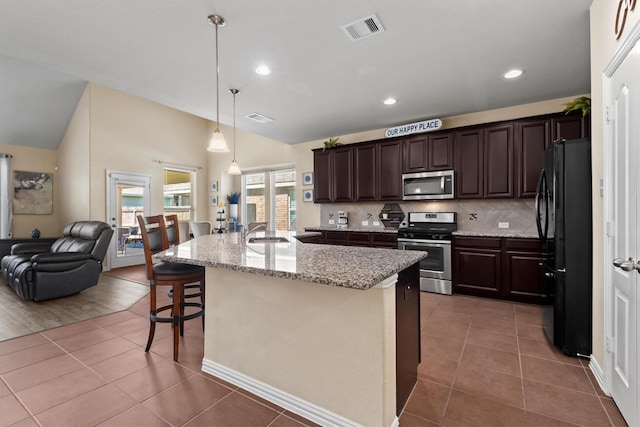 kitchen featuring stainless steel appliances, a sink, dark brown cabinets, vaulted ceiling, and visible vents