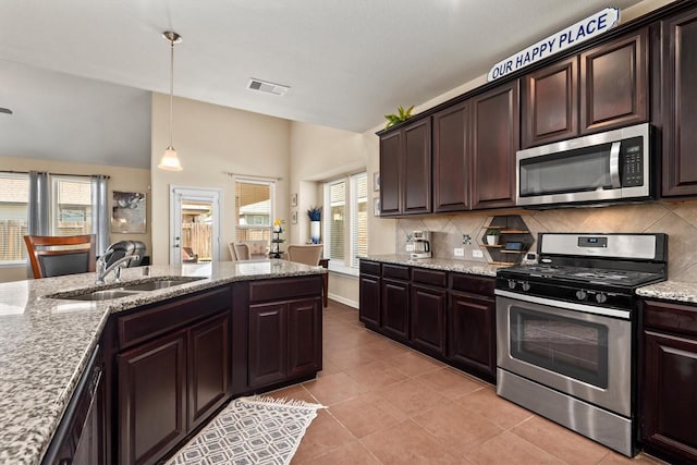 kitchen with a sink, visible vents, dark brown cabinetry, backsplash, and appliances with stainless steel finishes