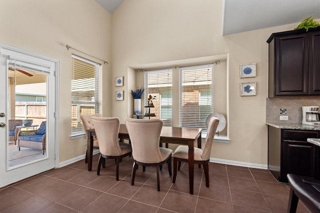dining room with baseboards, a ceiling fan, dark tile patterned floors, and plenty of natural light