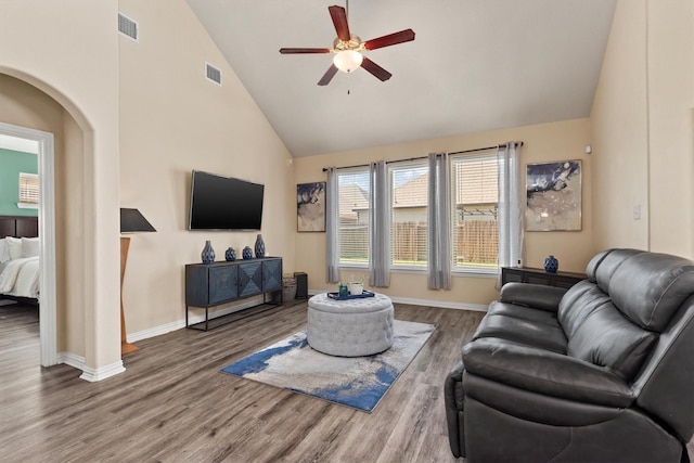 living area featuring wood finished floors, visible vents, baseboards, high vaulted ceiling, and ceiling fan
