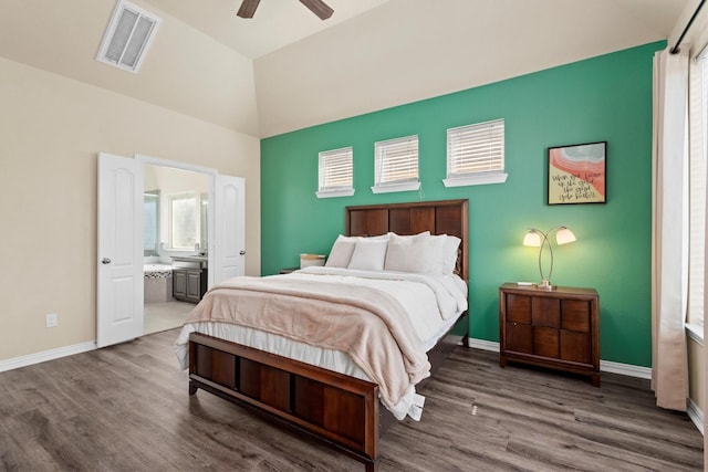 bedroom with wood finished floors, visible vents, ensuite bath, baseboards, and high vaulted ceiling