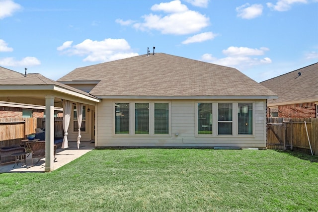 back of property with a lawn, a patio, a fenced backyard, and a shingled roof