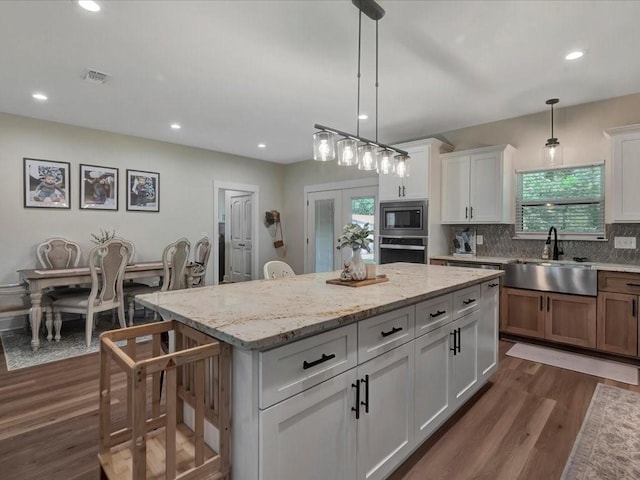 kitchen with a center island, dark wood-style floors, a sink, tasteful backsplash, and appliances with stainless steel finishes