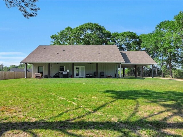 back of house featuring board and batten siding, a yard, and fence