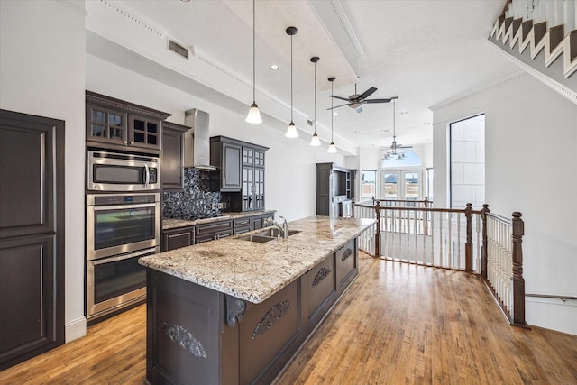 kitchen featuring stainless steel appliances, visible vents, a sink, wall chimney exhaust hood, and ceiling fan