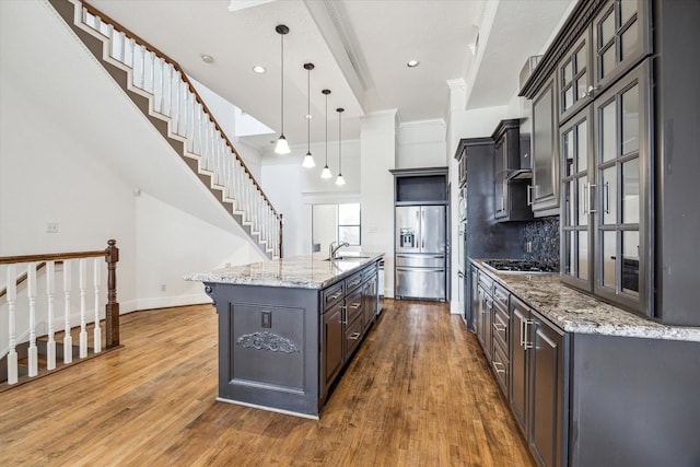 kitchen with wood finished floors, a kitchen island with sink, stainless steel appliances, and a sink