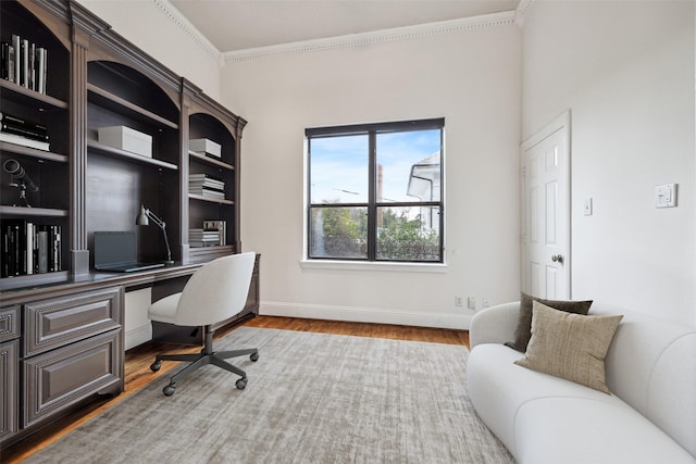 office area with built in study area, wood finished floors, crown molding, and baseboards