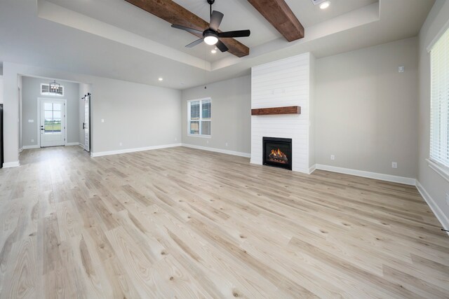 unfurnished living room featuring a tray ceiling, light wood-style floors, and a fireplace