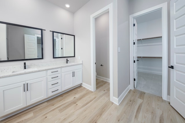 full bathroom featuring toilet, wood finished floors, a sink, double vanity, and baseboards