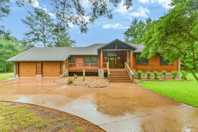 view of front of property featuring a front lawn, stone siding, a garage, concrete driveway, and covered porch