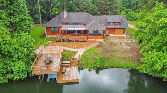 back of house with a deck with water view, a chimney, and a forest view