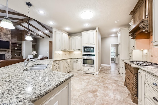 kitchen with light stone counters, hanging light fixtures, a sink, stainless steel appliances, and open floor plan