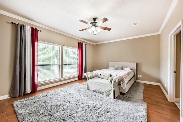 bedroom with visible vents, light wood finished floors, crown molding, and baseboards