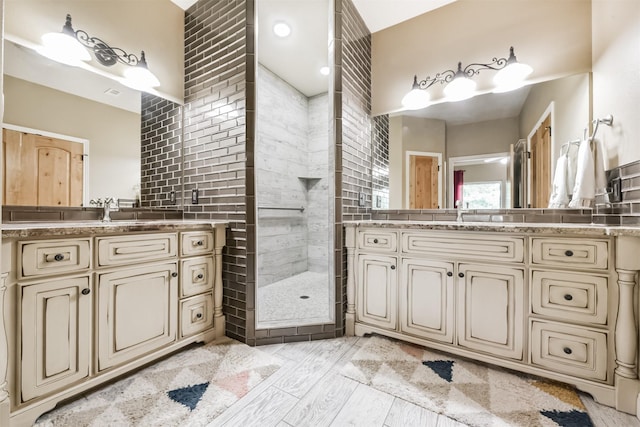 full bath with a sink, a walk in shower, and two vanities