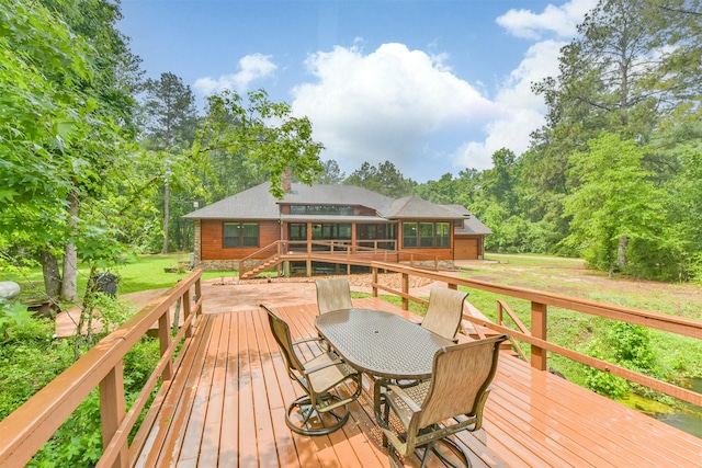 wooden deck with a yard, outdoor dining space, and a sunroom