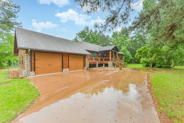 view of front of property featuring a front lawn, stone siding, roof with shingles, a sunroom, and concrete driveway