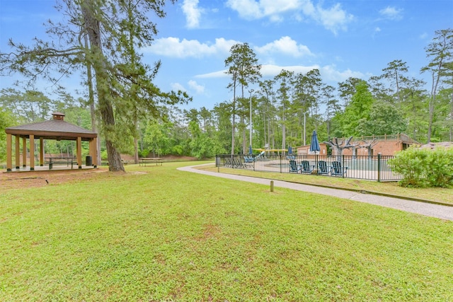 view of home's community featuring fence, a gazebo, playground community, a lawn, and a swimming pool