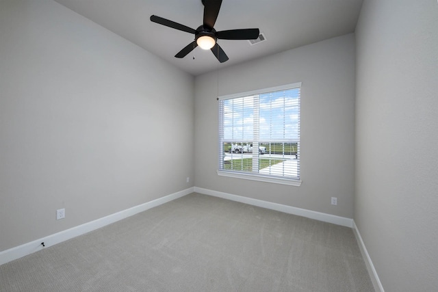 empty room with light colored carpet, baseboards, a ceiling fan, and visible vents