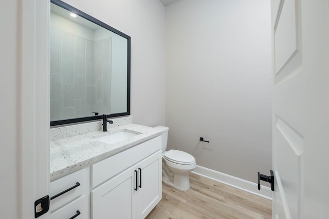 bathroom with baseboards, wood finished floors, toilet, and vanity
