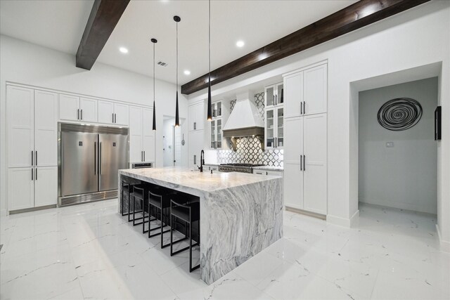 kitchen featuring light stone countertops, custom range hood, tasteful backsplash, beamed ceiling, and stainless steel built in refrigerator