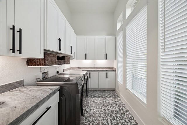 clothes washing area featuring cabinet space, a healthy amount of sunlight, and washer and clothes dryer