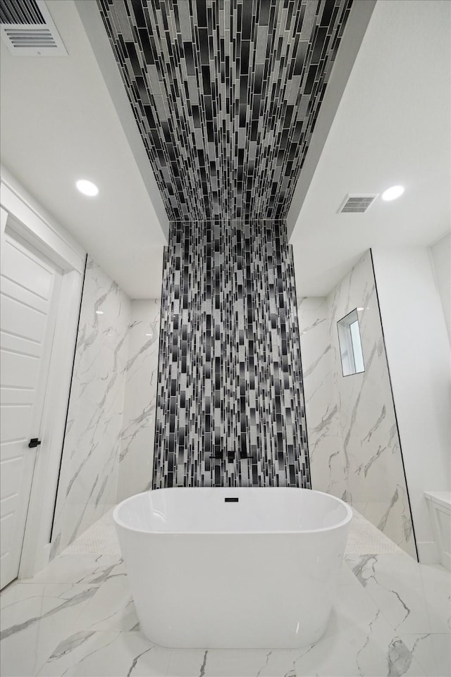 full bath featuring a freestanding bath, recessed lighting, and marble finish floor