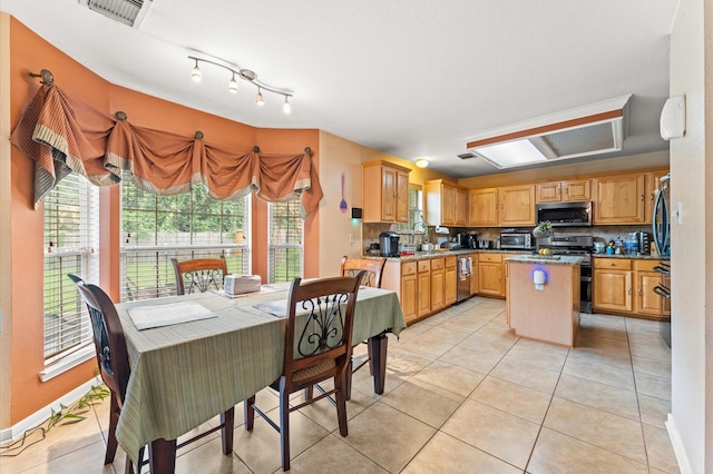 kitchen featuring light tile patterned flooring, appliances with stainless steel finishes, backsplash, a kitchen island, and visible vents