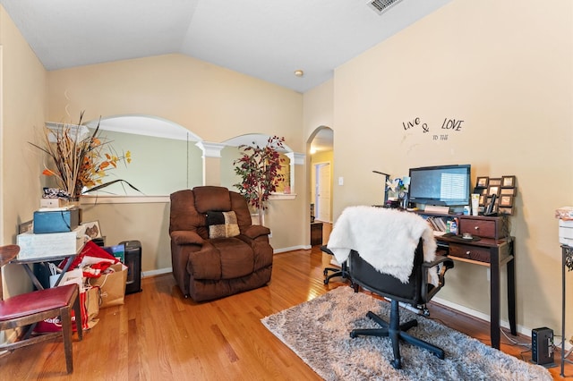 office area with visible vents, lofted ceiling, wood finished floors, baseboards, and arched walkways