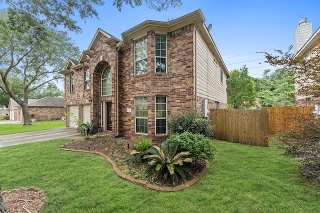 traditional-style home with brick siding, an attached garage, fence, and a front lawn