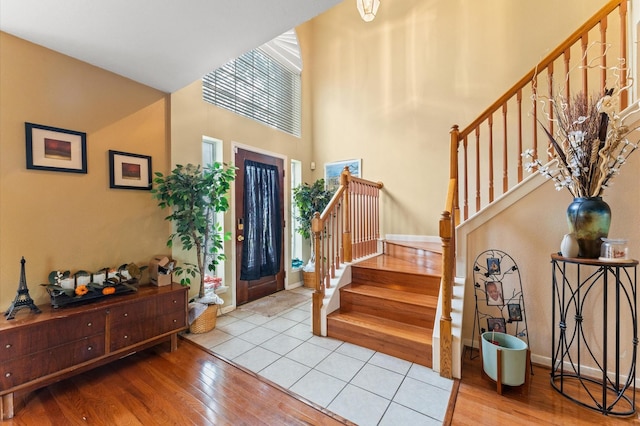 foyer with baseboards, stairs, wood finished floors, and a towering ceiling