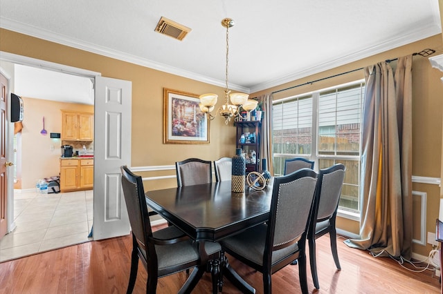 dining area featuring visible vents, baseboards, a chandelier, ornamental molding, and light wood-style flooring