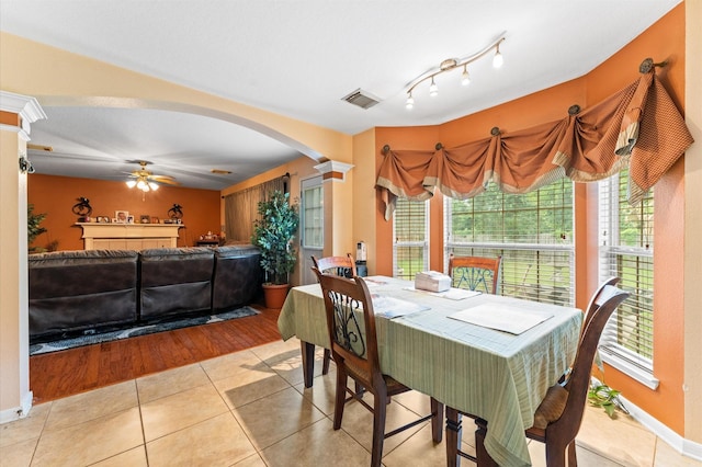 dining space with ceiling fan, decorative columns, visible vents, arched walkways, and light tile patterned flooring