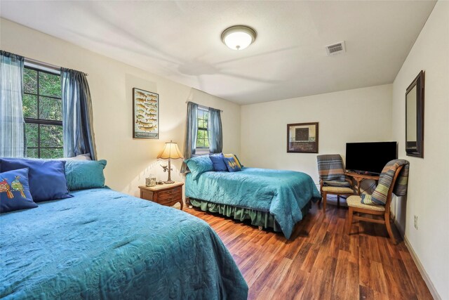 bedroom featuring baseboards, wood finished floors, and visible vents