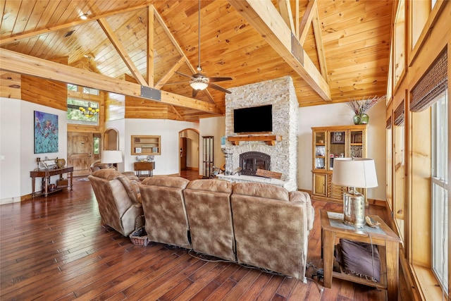 living area with beam ceiling, arched walkways, dark wood-style flooring, a ceiling fan, and wood ceiling