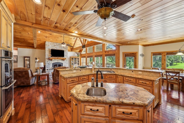 kitchen featuring wood ceiling, a stone fireplace, a large island, and ceiling fan