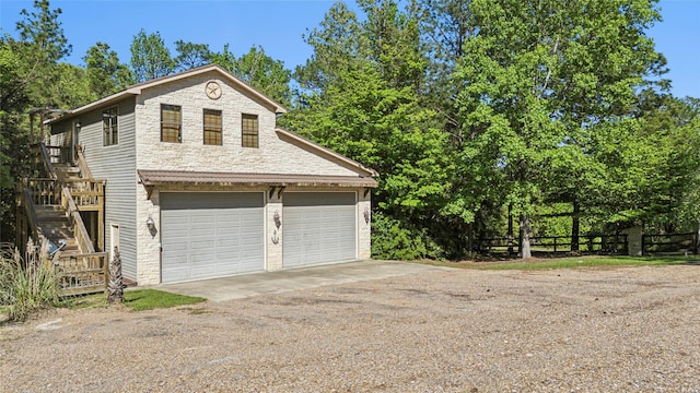 garage featuring dirt driveway and fence