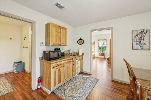 kitchen featuring black microwave, wood finished floors, visible vents, and a sink