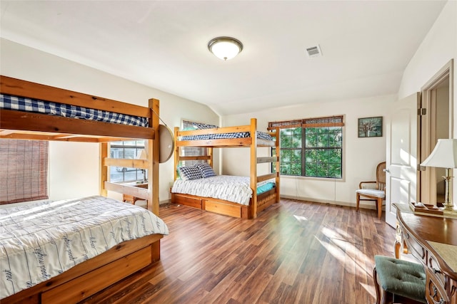 bedroom featuring lofted ceiling, baseboards, wood finished floors, and visible vents