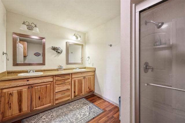 bathroom featuring wood finished floors, a sink, and a stall shower