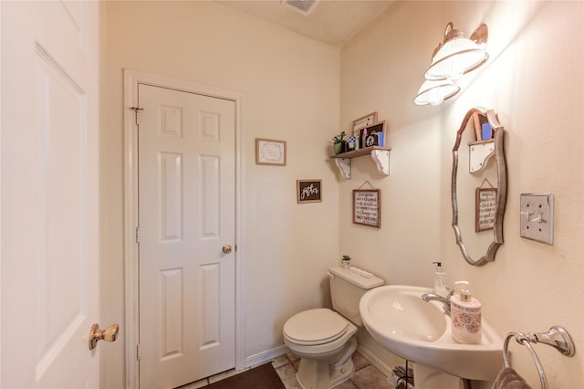 half bath with tile patterned flooring, visible vents, toilet, and baseboards