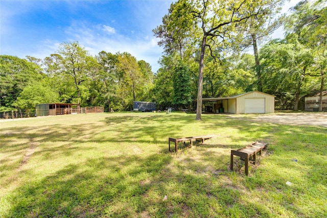 view of yard with a garage, an outbuilding, and fence
