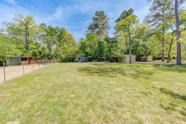 view of yard with a storage shed, an outbuilding, and fence