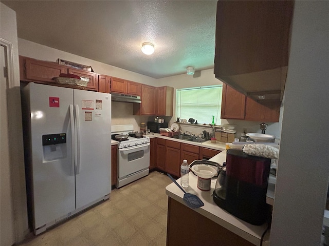 7810 Sawmill Trl, Houston, TX 77040 - kitchen with white appliances, under cabinet range hood, light floors, brown cabinetry, and a textured ceiling